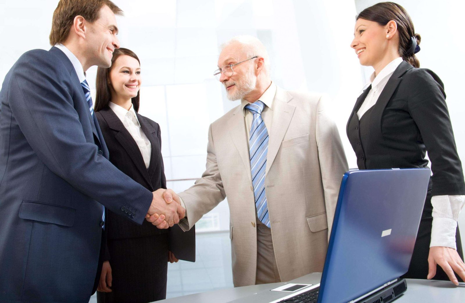 Group of four business people shaking hands in an office